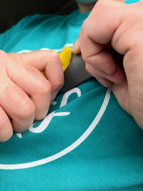 Two hands position a seat belt knife in order to cut free from the belt. A seat belt knife is a must when choosing what to pack in a car emergency kit.