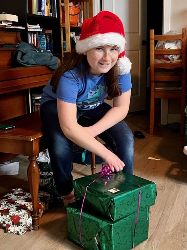 Our daughter in her Santa hat ready to open a big green present. 