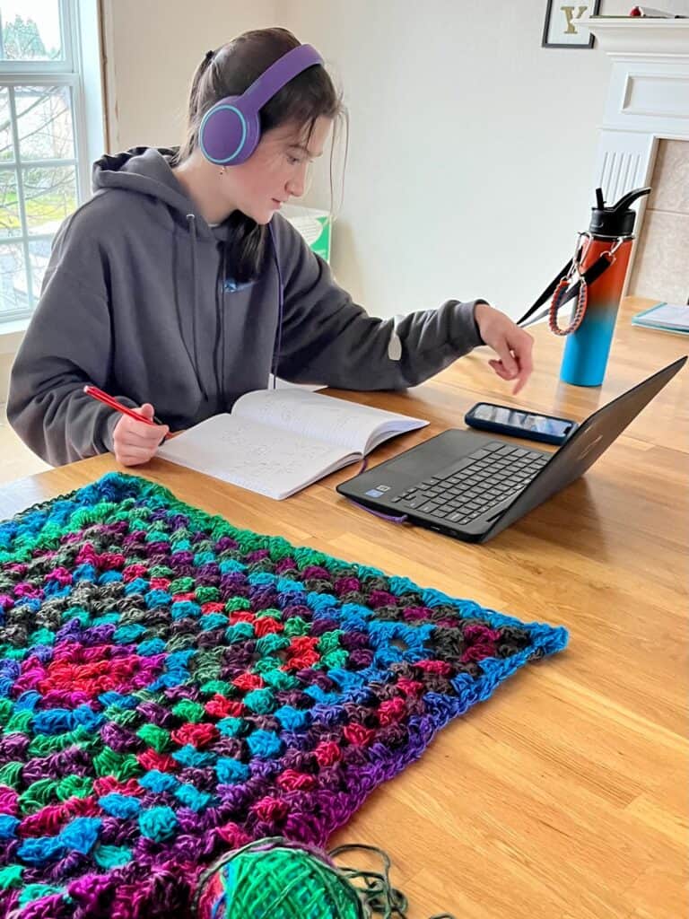 Rook hard at work on school with her crochet project next to her.