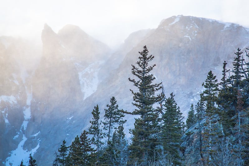 Sunlight and mist intermingle beside snowy peaks at Rocky Mountain National  Park. Rocky Mountain National Park is one of the best national parks to visit in November and December.