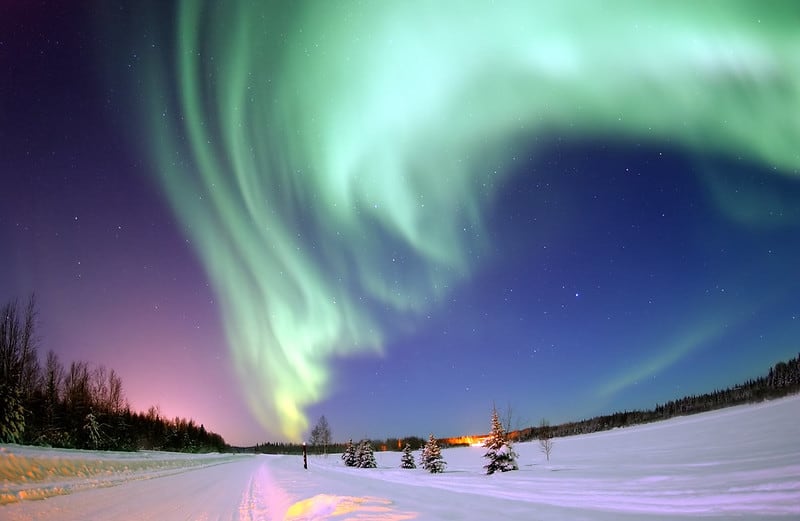 Northern lights glow over a winter landscape.