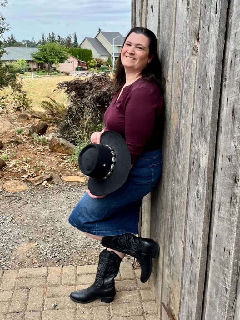 Jenn in Western outfit with burgundy shirt, black cowboy hat, black boots and denim skirt. Gifts for cowgirls.