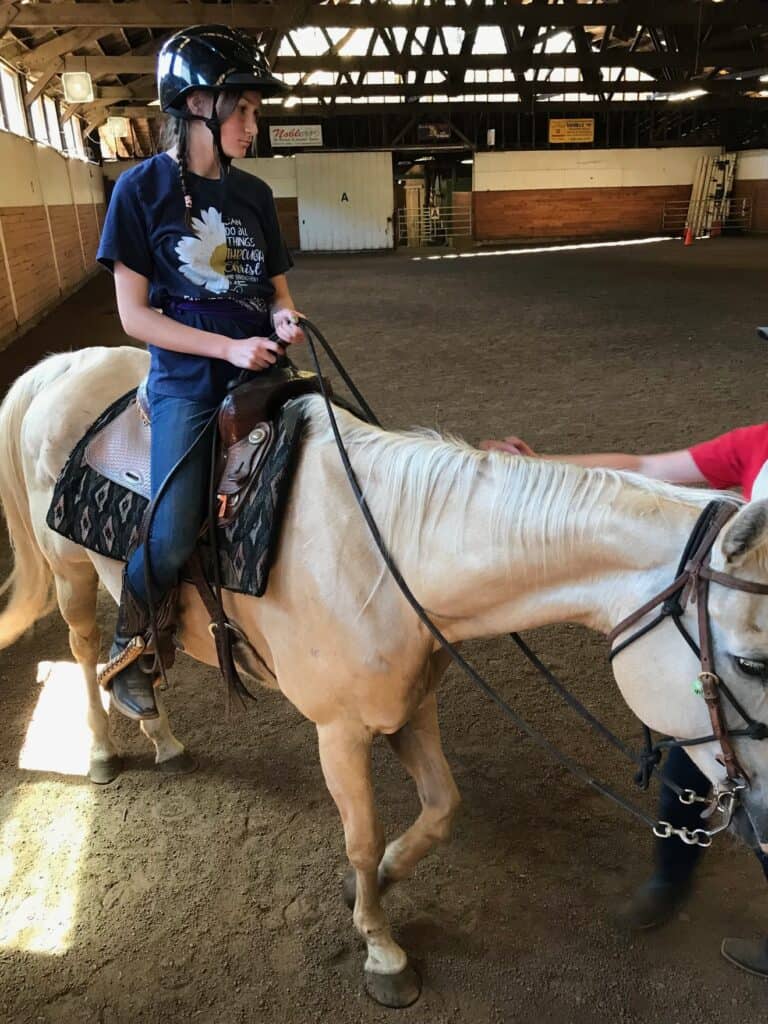 Our daughter on a horse in the equestrian ring at horse camp. Gifts for cowgirls.