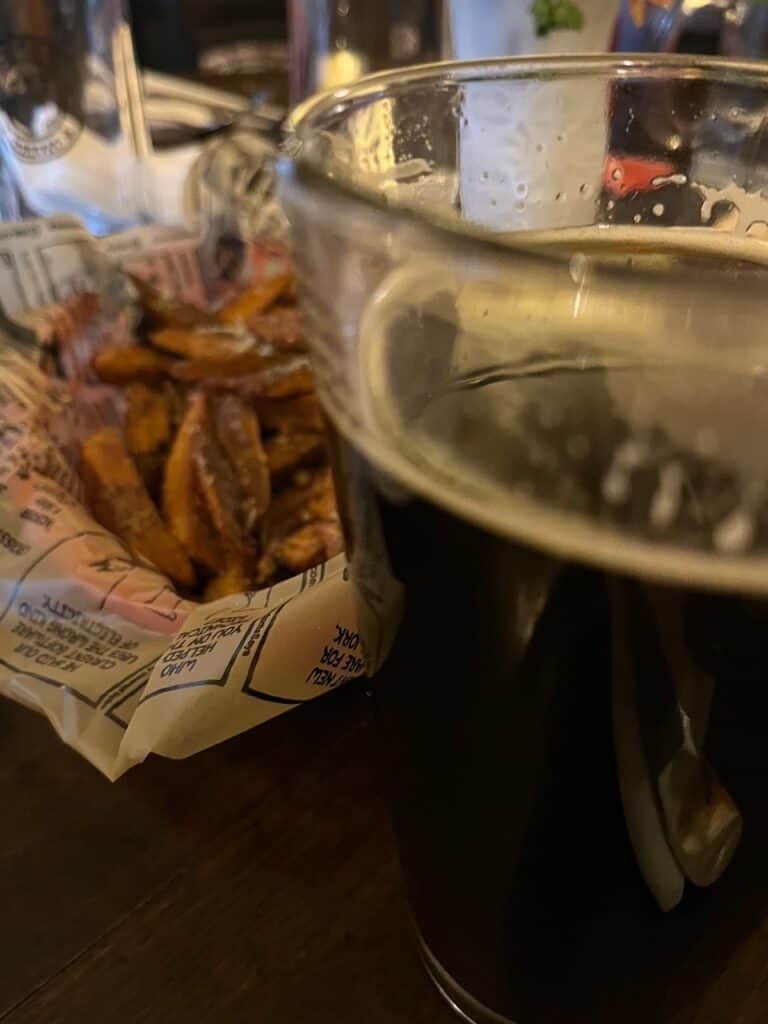 A glass of craft beer and parmesan fries sits at a table at Wolf Creek Tavern.