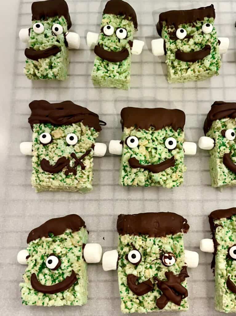 Frankenstein Rice Krispie treats. Green Rice Krispie treats with marshmallow bolts, dipped chocolate hair, candy eyes and piped chocolate mouths.