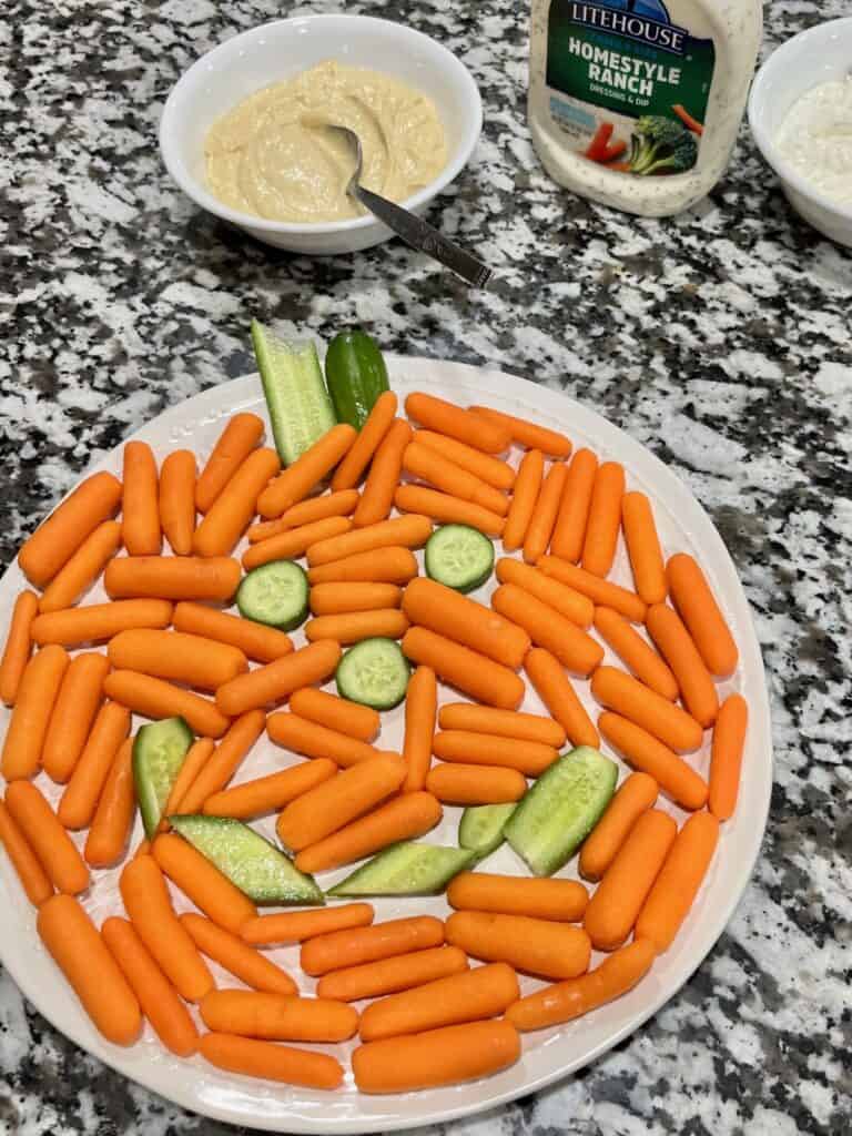 Easy Halloween party snack: carrots and cucumbers in a jack-o-lantern design with dips. 