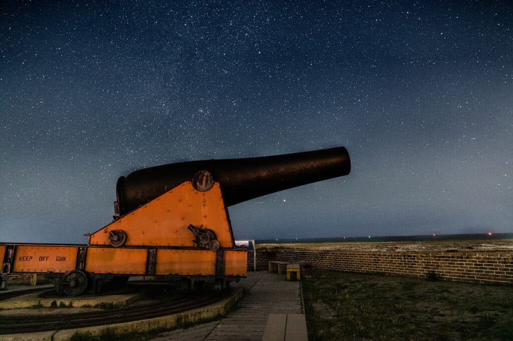A cannon stands perched atop a historic fort on a starry night at Gulf Shores National Seashore. Gulf Shores National Seashore is one of the best national parks to visit in November and December.