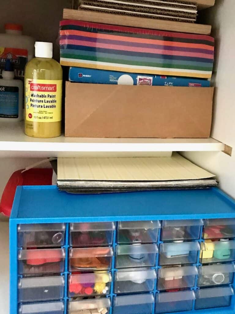 Our craft supply cabinet with colored paper, paper punches, pom poms, glue, paint and more.