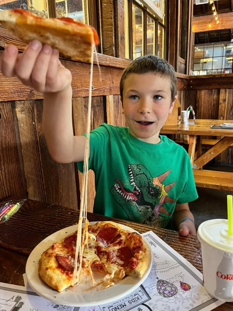Our son gawks at the thick string of cheese that stretches from his piece of pizza and the remaining pie.