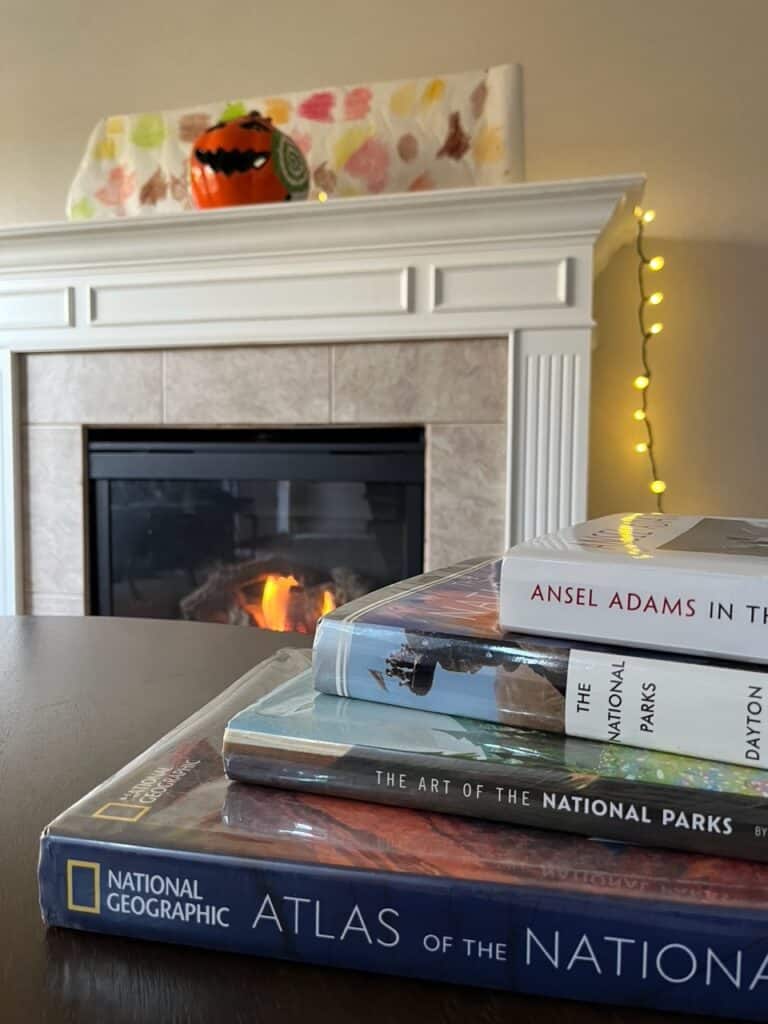 Beautiful national park coffee table books sit on a coffee table in a warm living room. Excellent coffee table books are a great choice when looking for the best books on national parks.