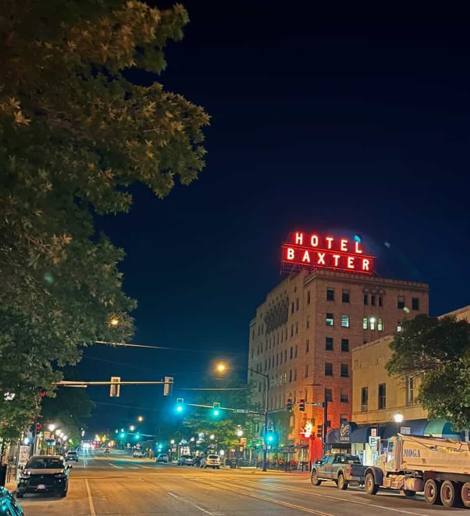 The lit sign of the Hotel Baxter dominates a night scene in Bozeman, Montana. Bozeman is a great place to experience the best restaurants in Montana.