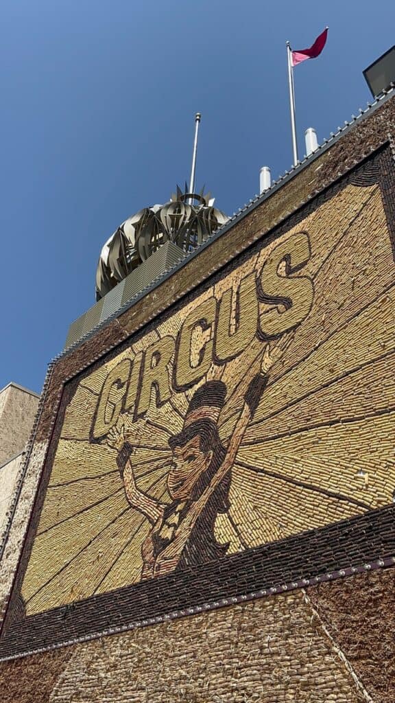 A ringleader woman stands under the word "Circus" on an enormous corn mural at the Corn Palace. The World's Only Corn Palace is one of the best things to do in Mitchell SD.
