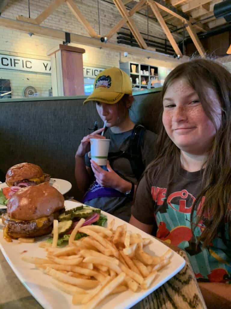Our daughter smiles beside her Smashburger and fries. Montana Ale Works is one of the best restaurants in Montana.