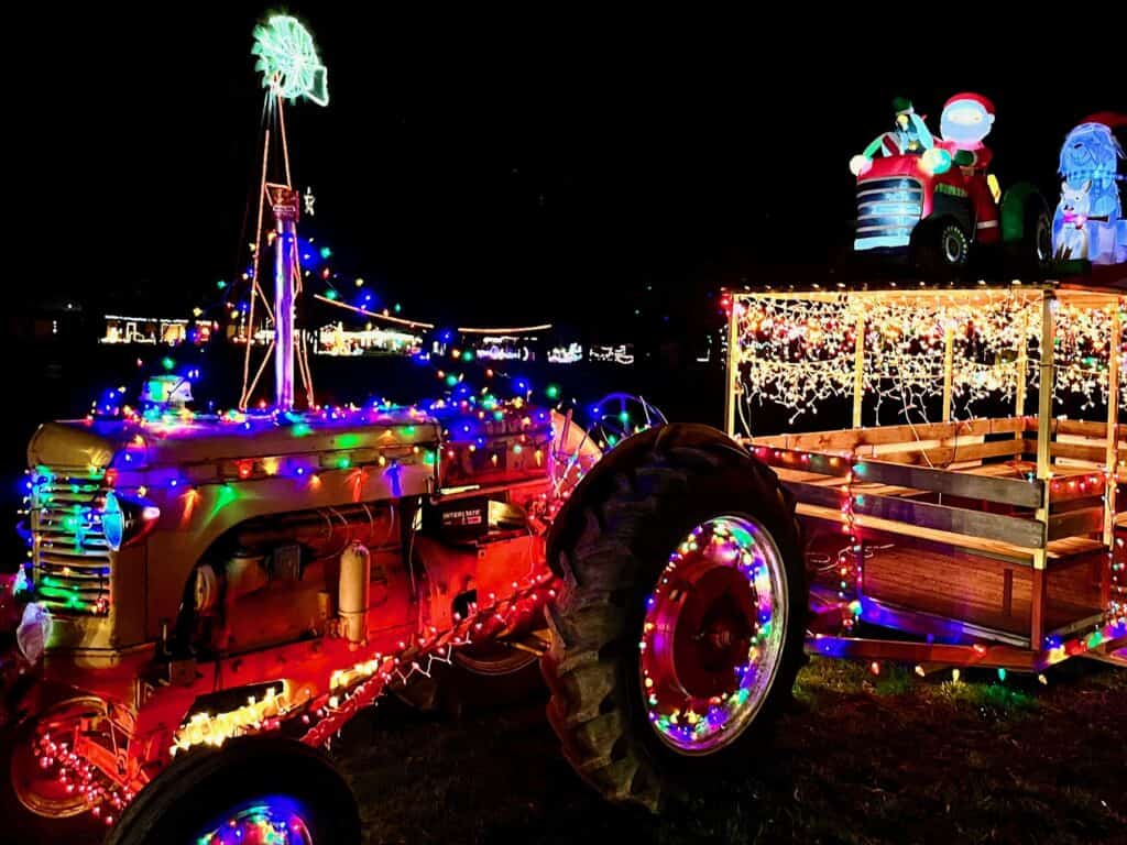 Antique tractor pulling a tram all decked out with Christmas lights and inflatables on the tram roof. Powerland Holiday Sparkles in Brooks, Oregon.