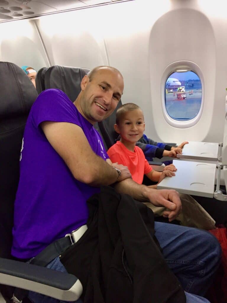 Brian and our son smile from the airplane cabin seats.