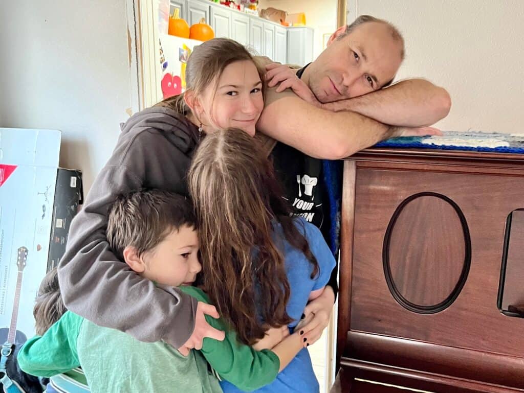 Brian and some of our kids hugging by the piano. How to make the holidays ADHD friendly
