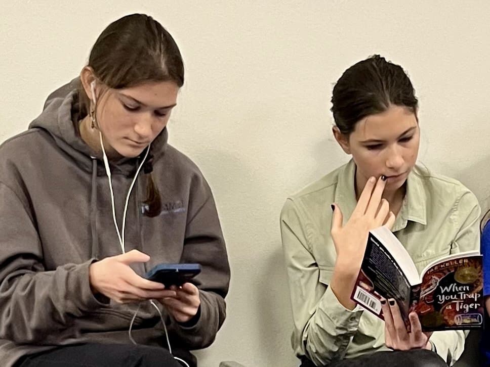 Our oldest teen daughters waiting while listening to music and reading a book