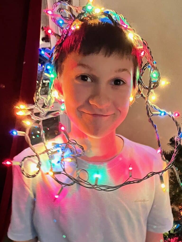 Our son with Christmas lights around his head. Making the holidays ADHD friendly.