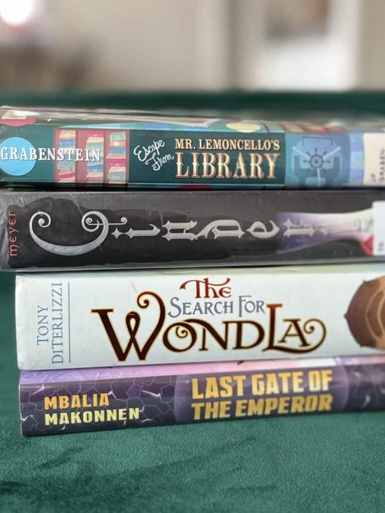 Stack of books showing the spines: Last Gate of the Emperor, The Search for Wondla, Cinder and Escape from Mr. Lemoncello's Library.