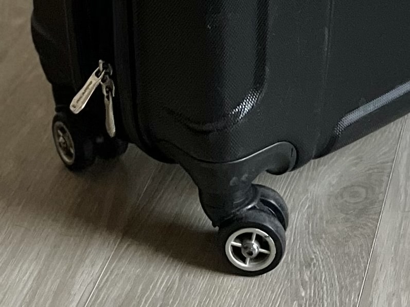 Close up of black rolling suitcase wheels.
