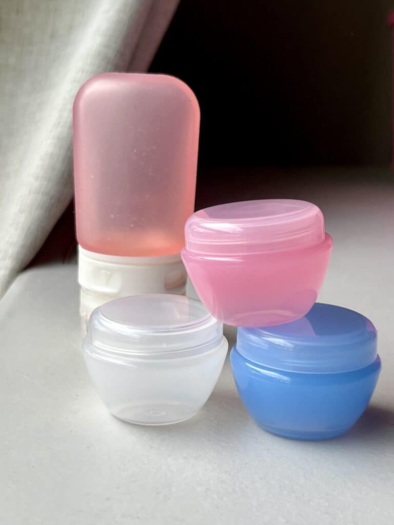 Travel sized shampoo container and 3 multicolored tiny containers for pills or creams.