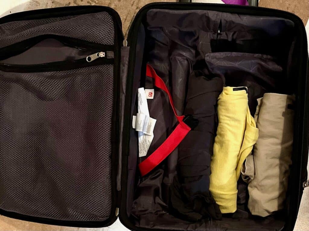 Open suitcase with rolled clothes on one side. What to pack in a carry on for a teenager