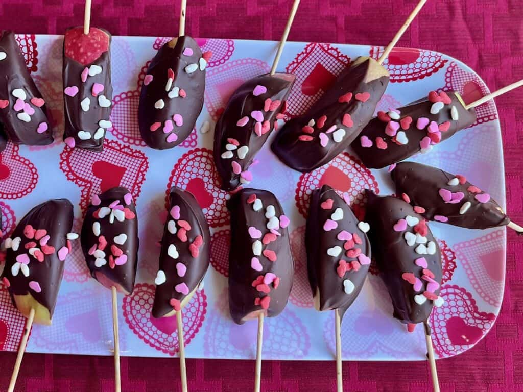Chocolate dipped apple slices on a heart plate.