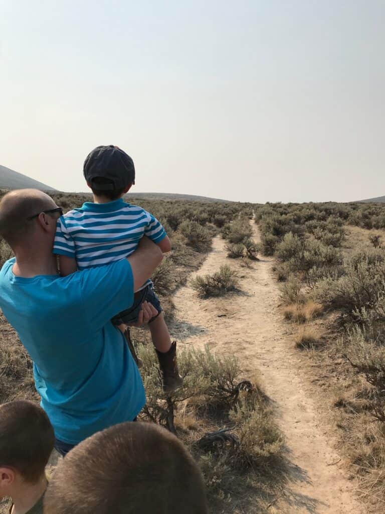 Brian holds up our son so that he can better see the Oregon Trail ruts.