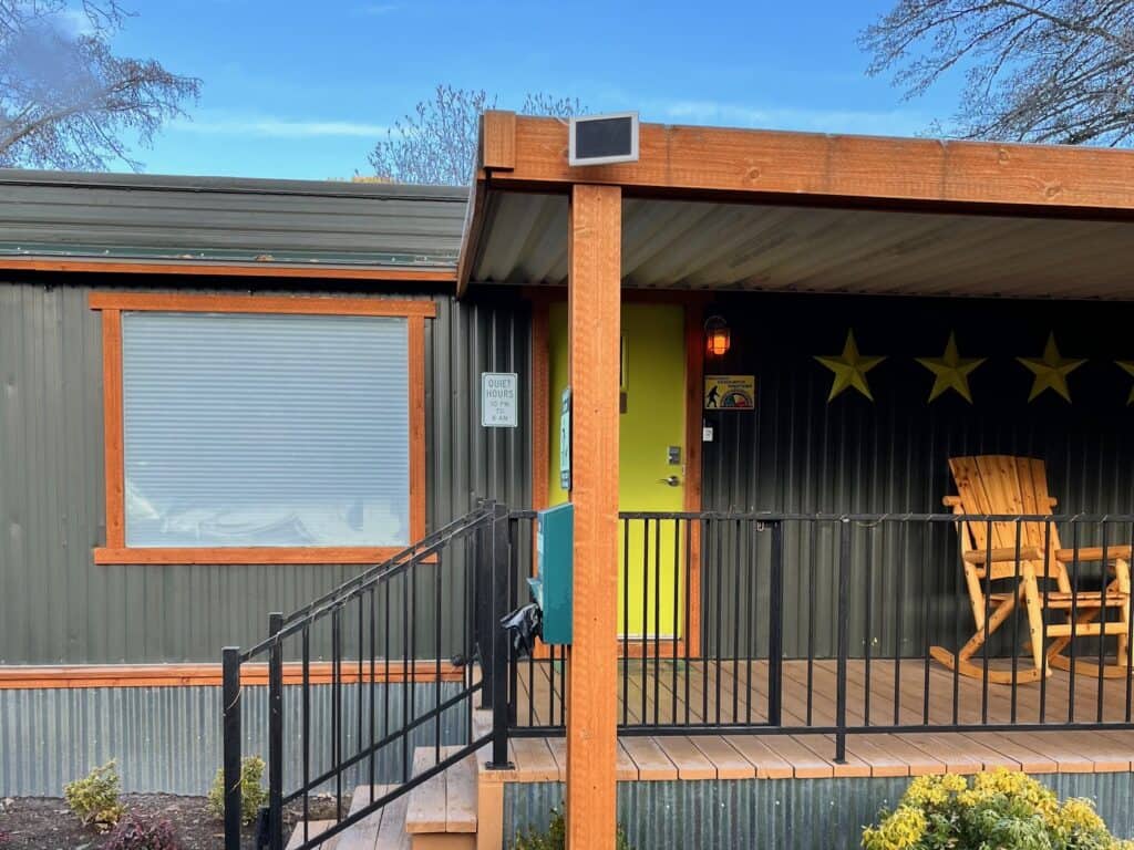 A manufactured home with a deck and a sign that says "Quiet hours" by the door.