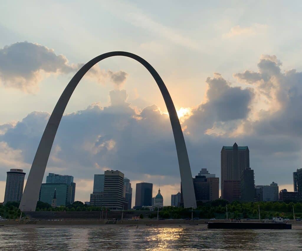 The sun peaks from behind the Gateway Arch at Gateway Arch National Park.