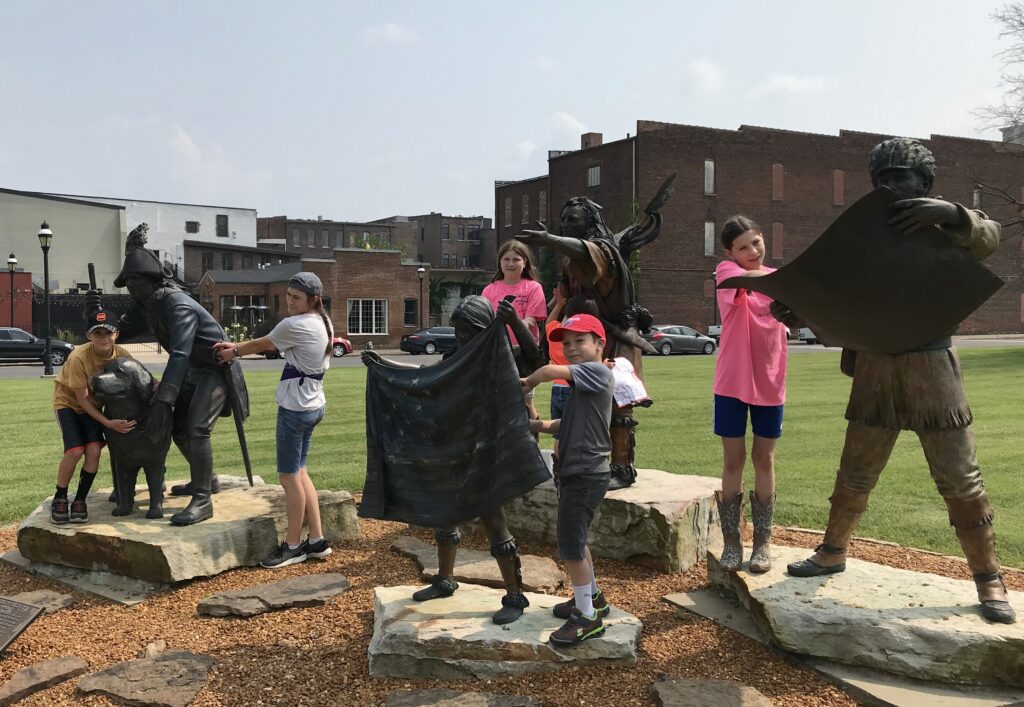 My children pose beside bronze statues of Lewis & Clark.