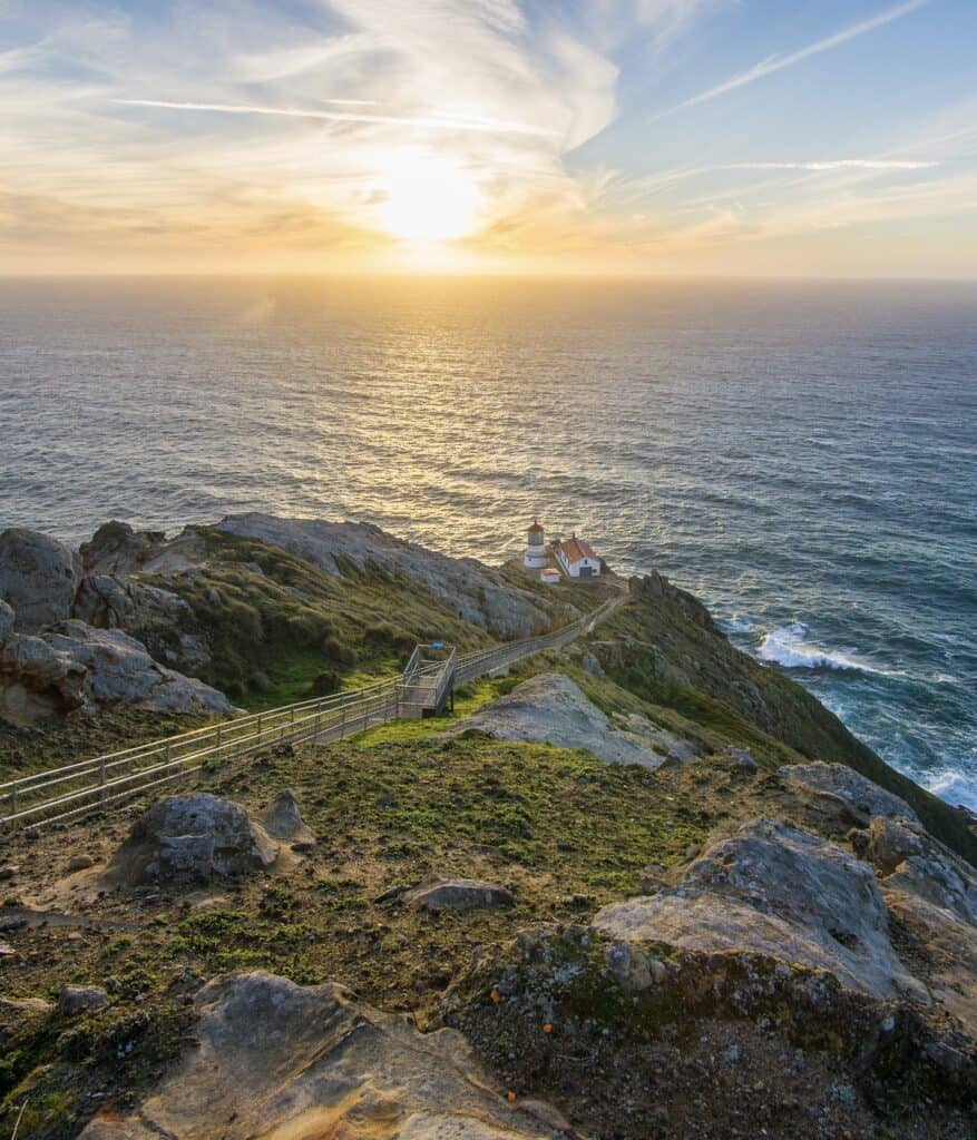 The Point Reyes Lighthouse keeps watch as the sun sets over the ocean.