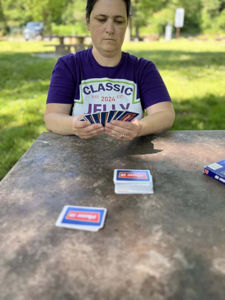 Jenn in purple shirt playing Phase 10 at a picnic table