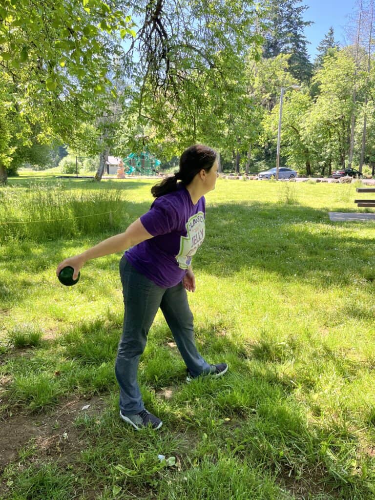 Jenn in purple shirt preparing to toss bocce ball at a picnic area