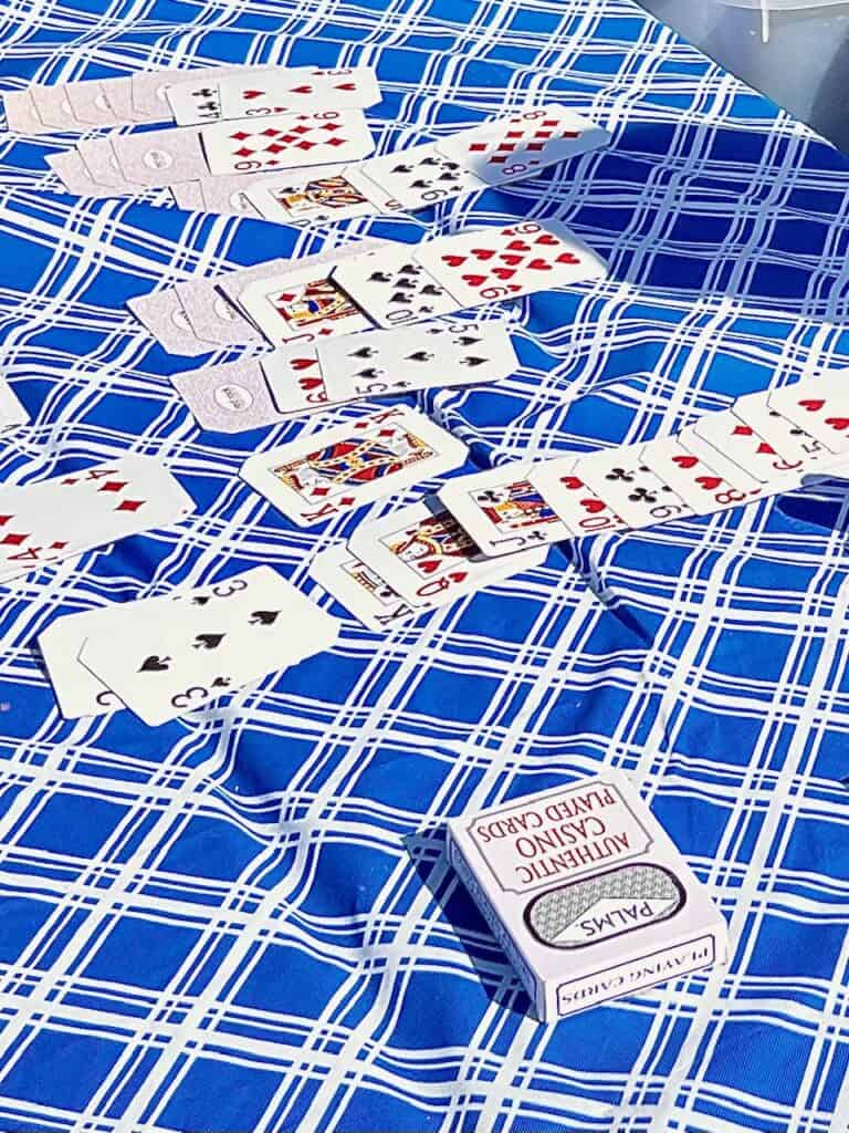 Deck of cards set up for solitaire on a plaid blue and white tablecloth