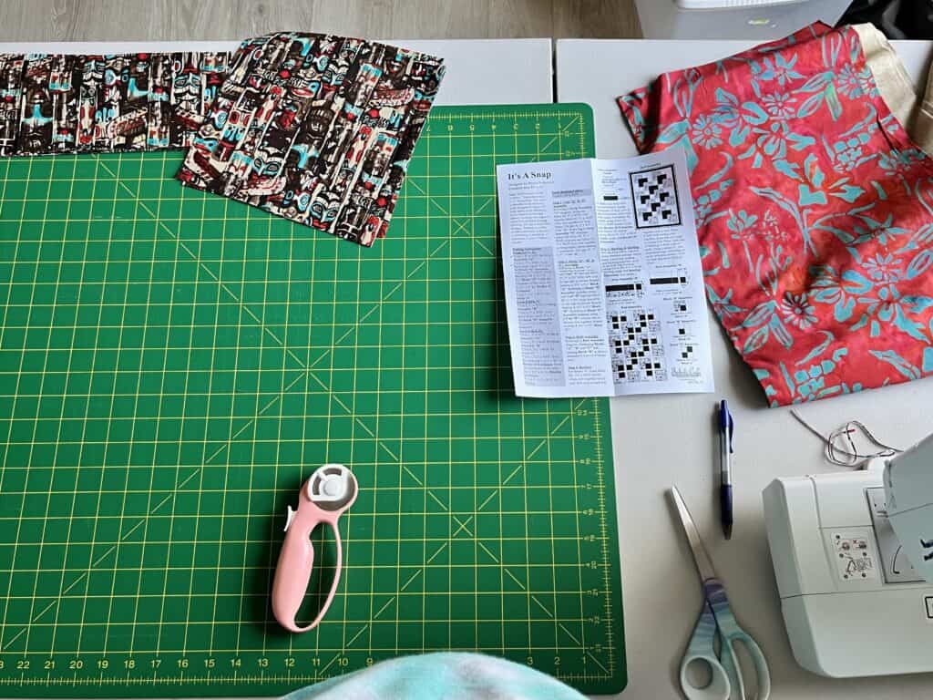 cutting board with fabric and pattern next to a sewing machine
