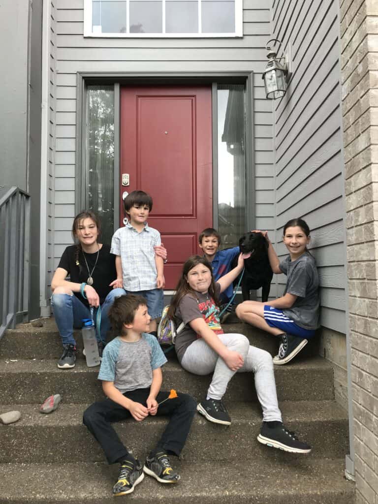Our six children with our black Labrador dog on the front steps of our home.