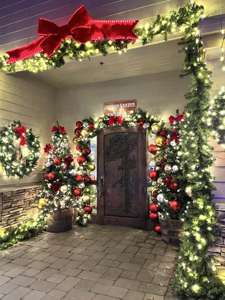 Entrance door to the Oregon Garden Resort, fully decorated for Christmas with lights, evergreen garland, red and gold bows and ornaments.