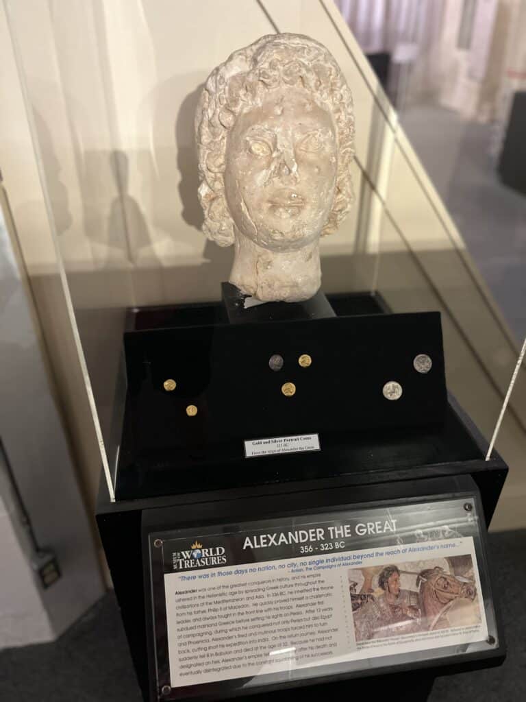 sculpted head of Alexander the Great along with ancient coins
