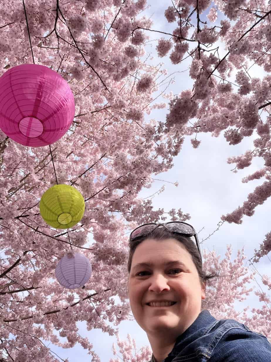 Jenn smiles under the cherry blossoms and lanterns at the Oregon Capitol State Park