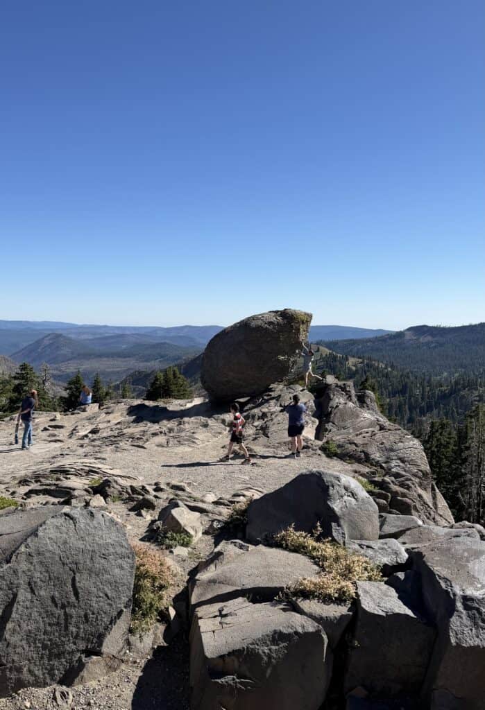Our family explores a rocky outcropping. One of our sons pretends to hold up an enormous boulder at Lassen National Volcanic Park.