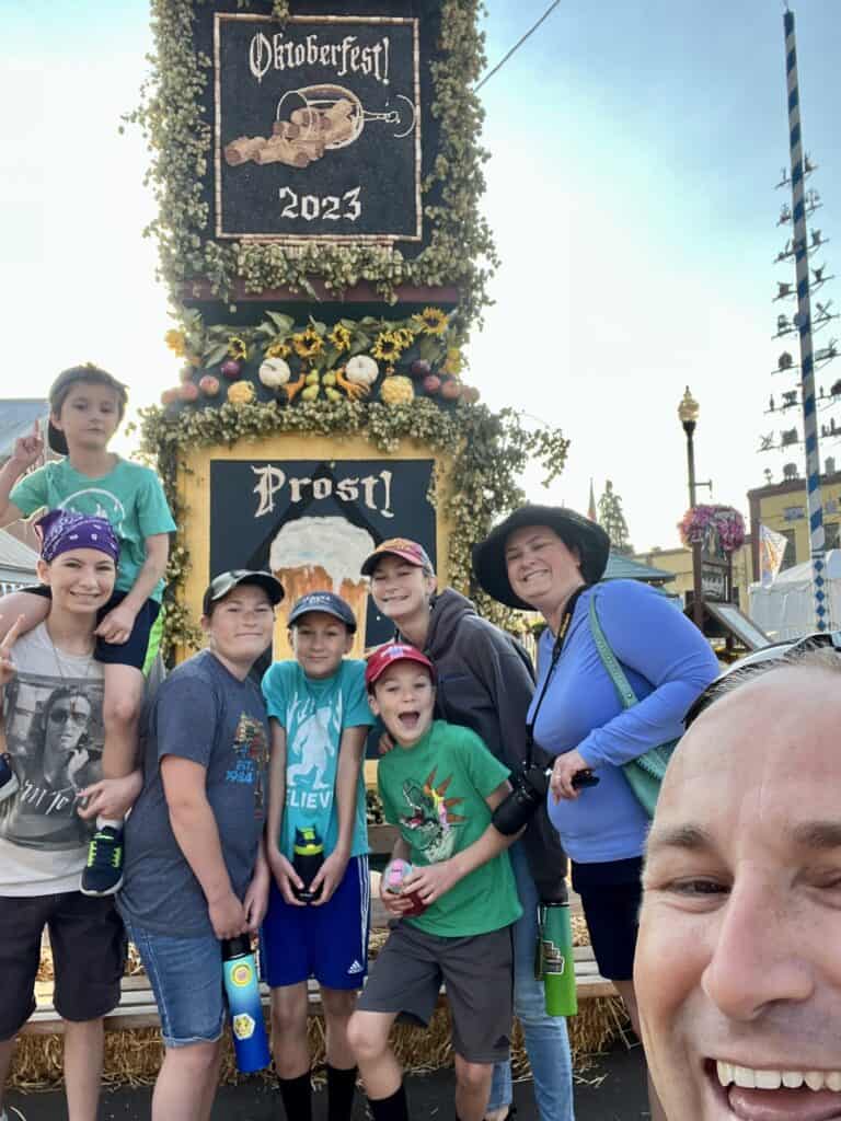 Our family smiles in front of a celebratory tower at Oktoberfest in Mt. Angel, Oregon. Mt. Angel is one of the 15 hidden gems of Oregon.