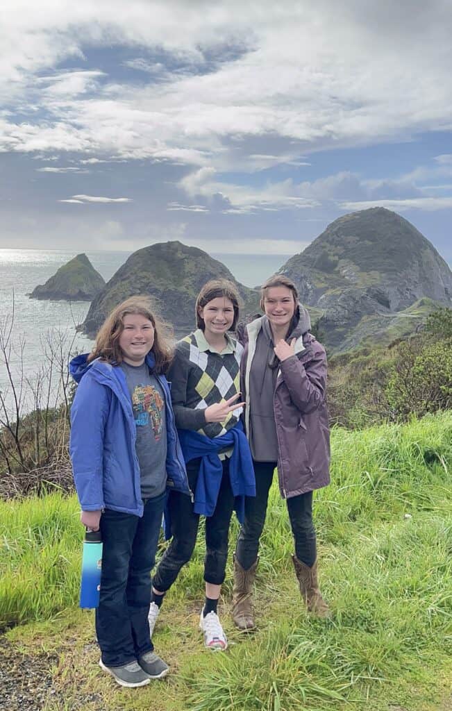 Our daughters smile in front of the incredible landscape of the Southern Oregon Coast.