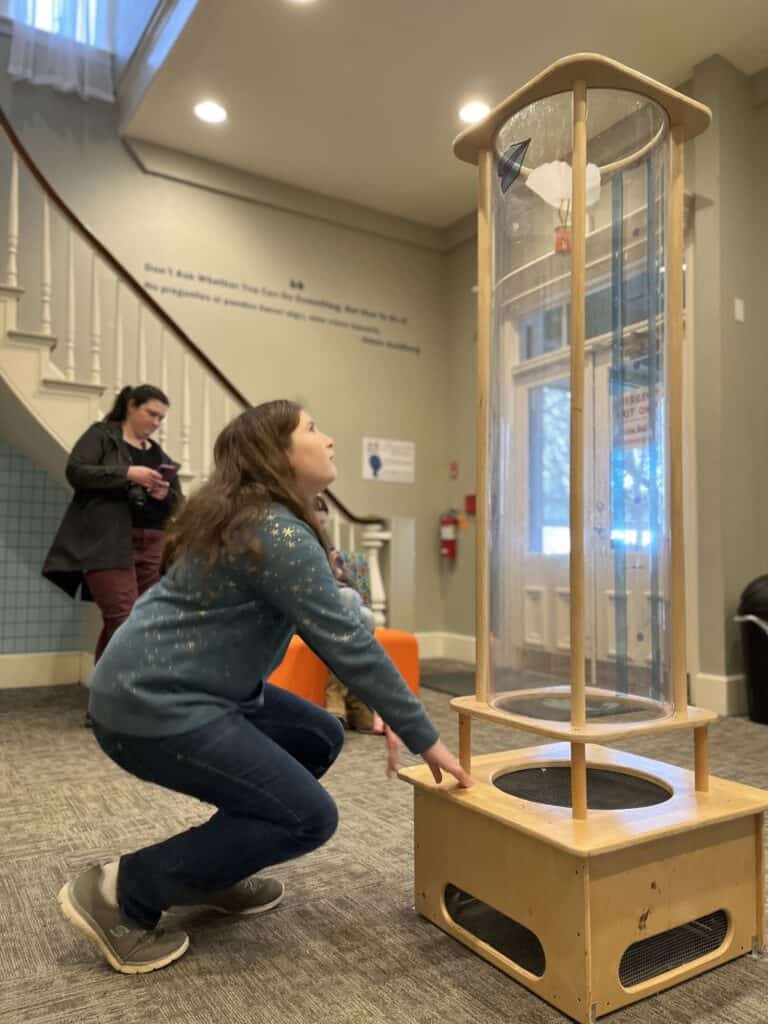 Our daughter watches her constructed vehicle fly up a wind tube at the Gilbert House Museum in Salem, Oregon.