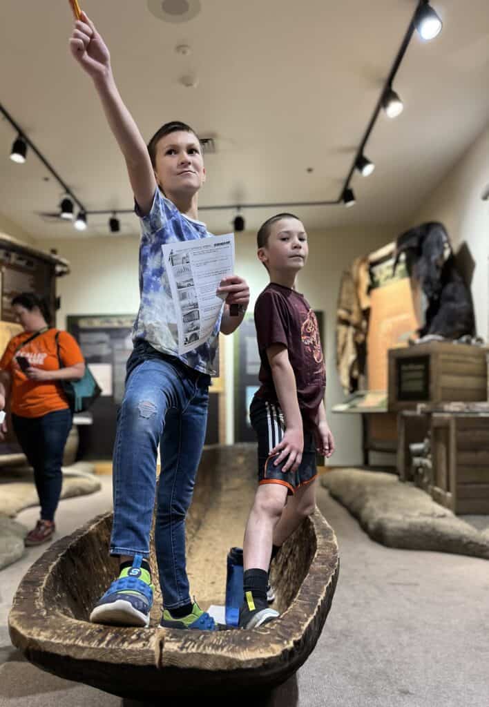 Our boys stand dramatically in a dugout canoe at a museum in the Dalles, Oregon.