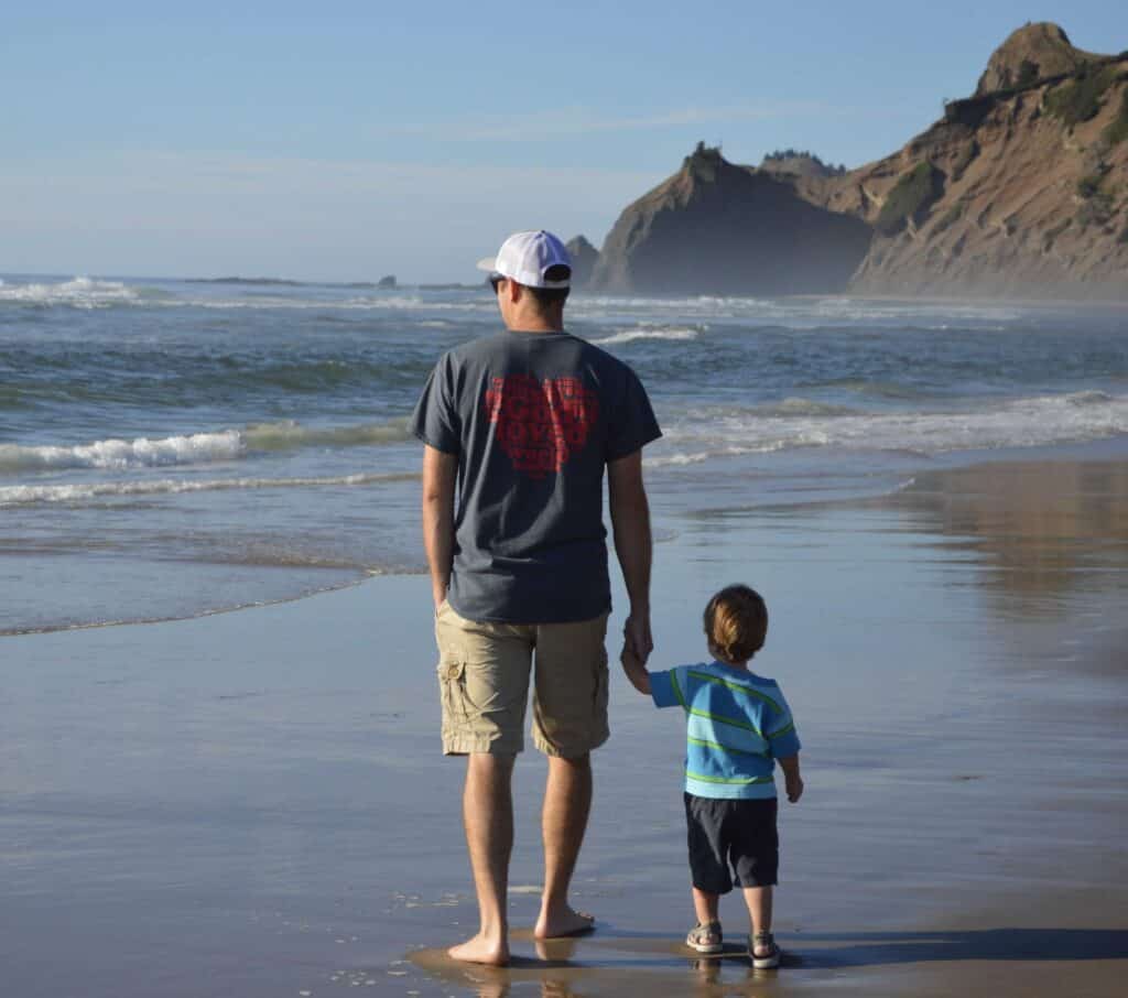 My infant son and I hold hands while standing on a beautiful beach at Lincoln City.