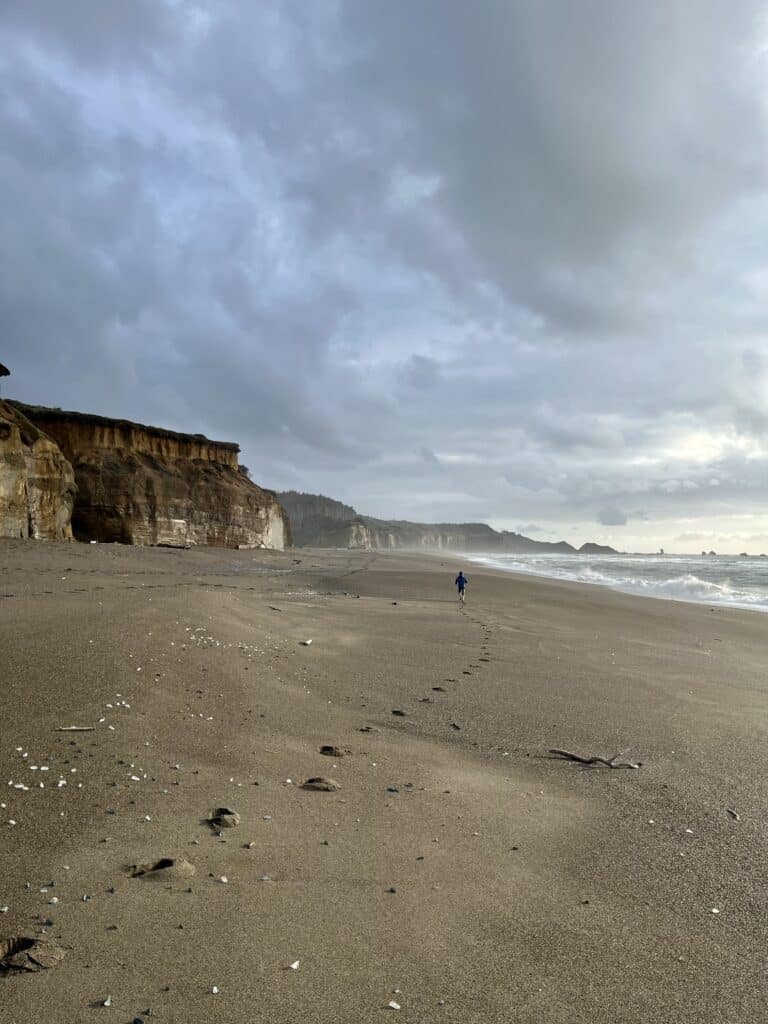 Our child walks along the shore of an empty beach at the Blacklock Cliffs. We found so many amazing things to do on the Southern Oregon Coast with kids.