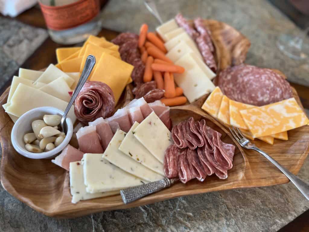 Meats, cheeses and condiments artfully displayed on a charcuterie board.