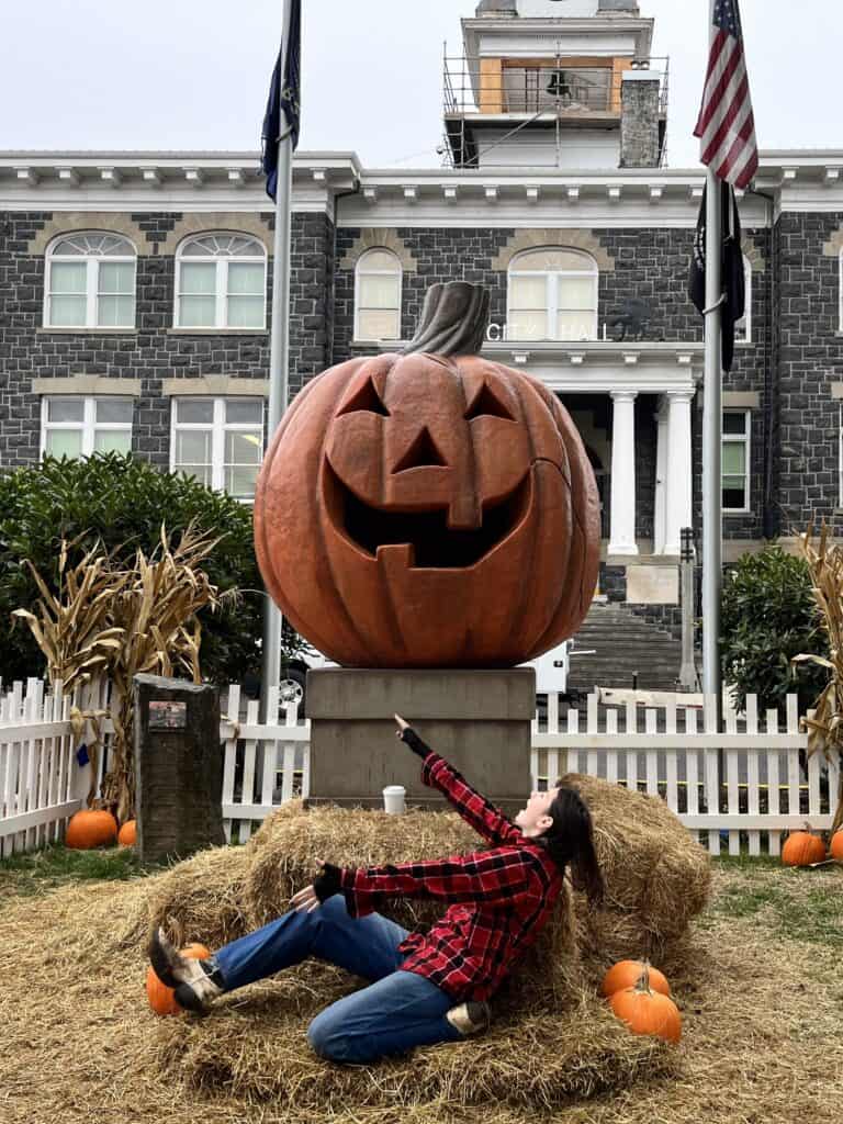 My daughter sits in front of the giant jackolantern in Town Square at Halloweentown