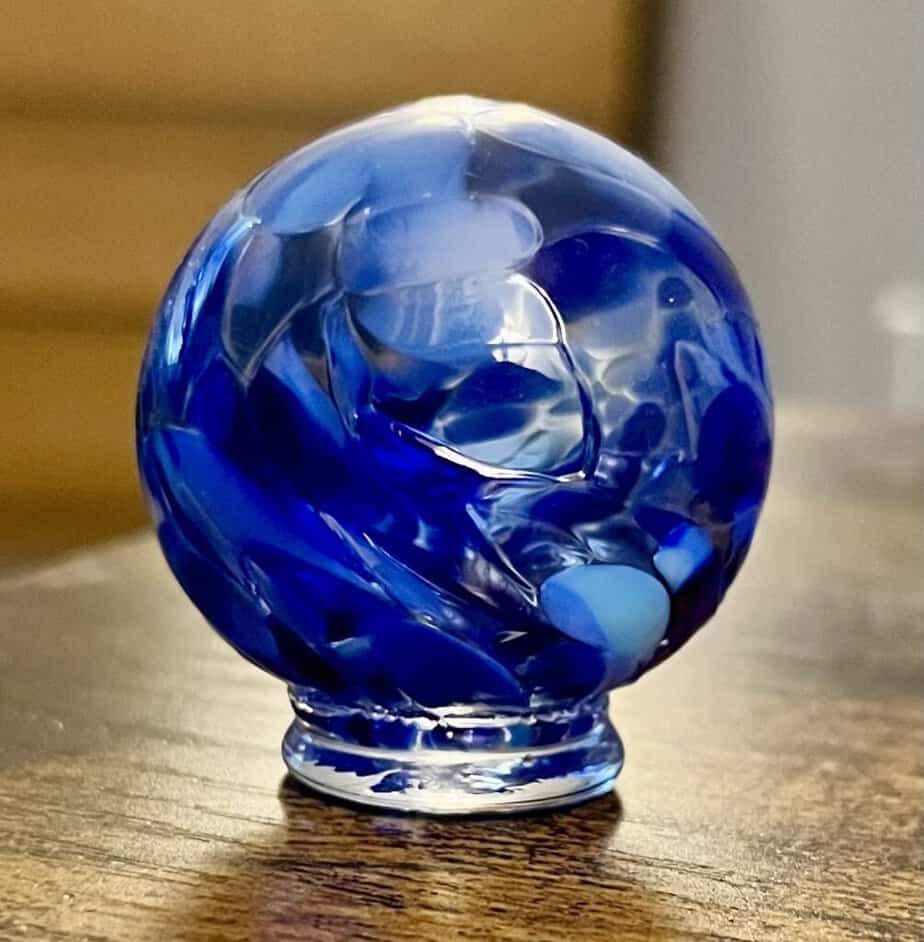 An art glass orb sits on a desk at our home.